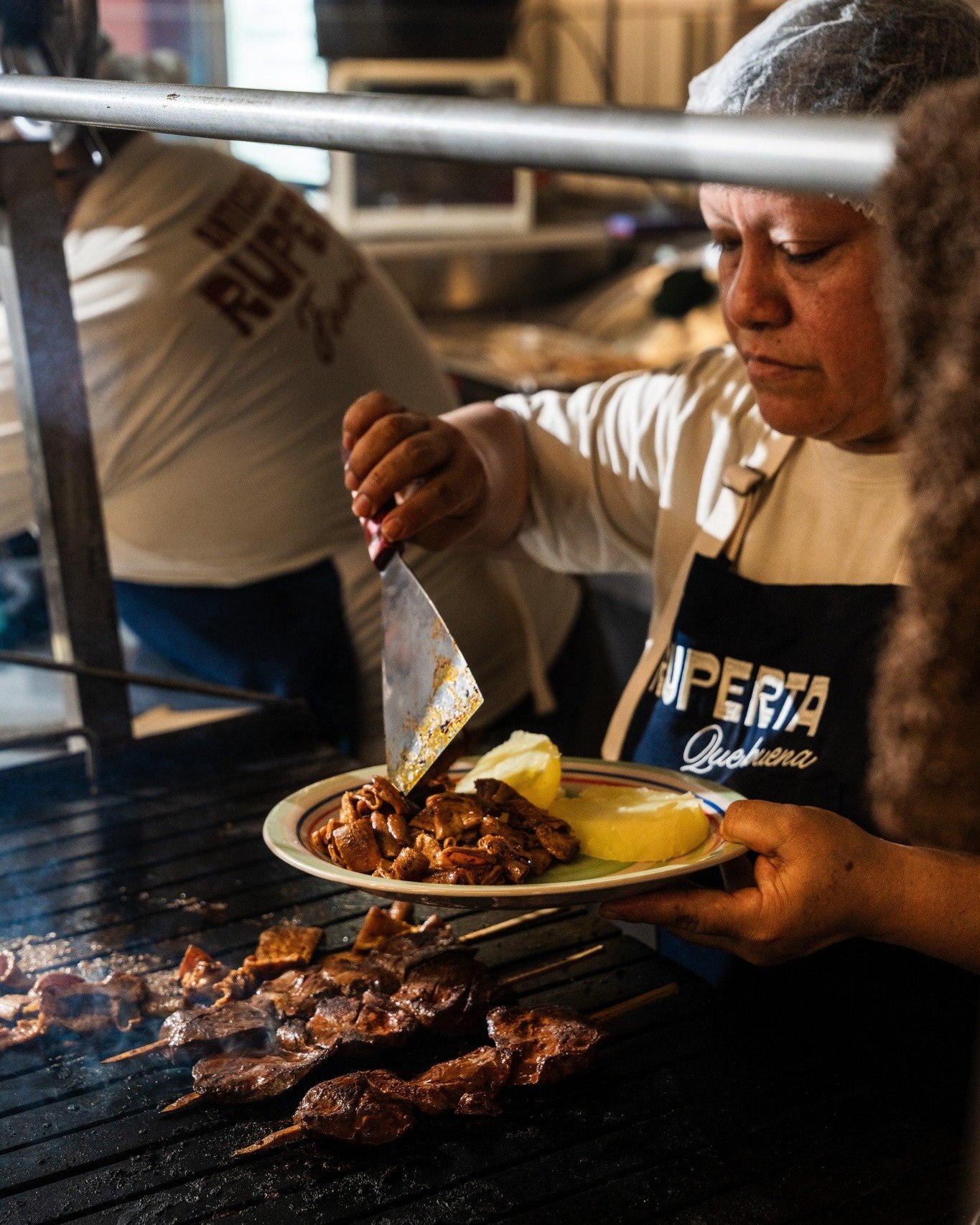 Cocinera de Ruperta sirviendo un plato de anticuchos